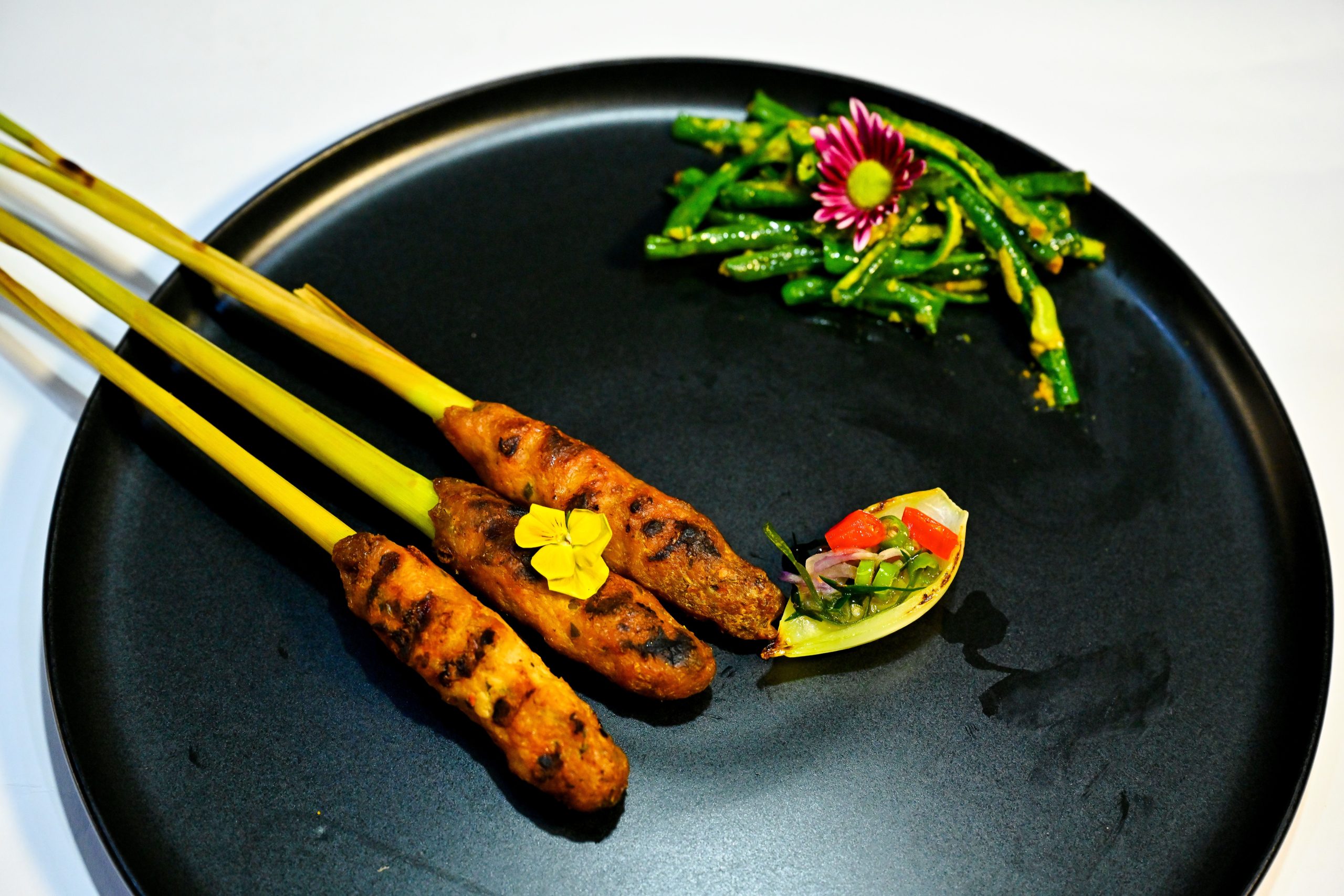 Balinese sate lilit skewers served with herbs and traditional side dishes.