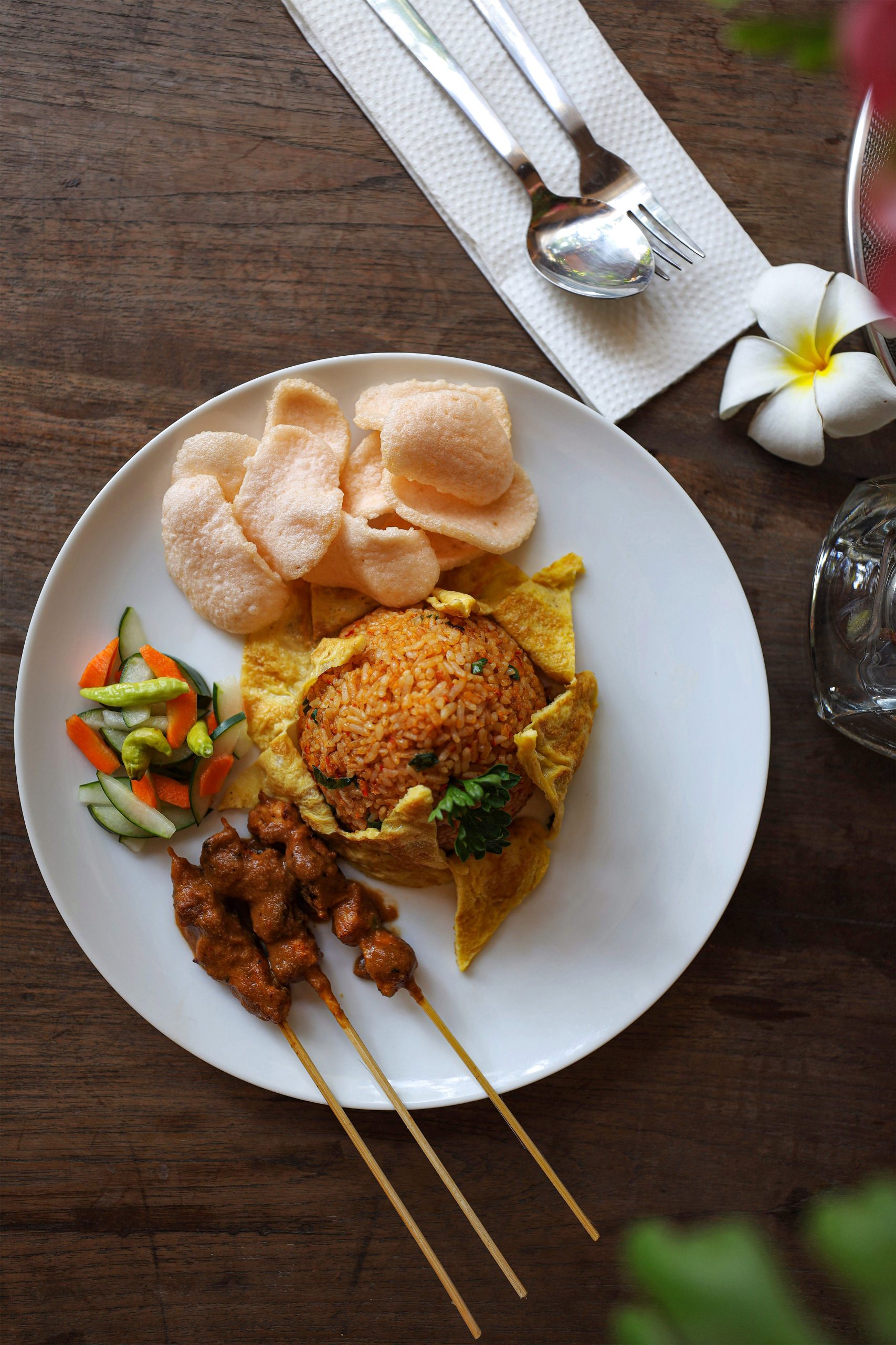Indonesian nasi goreng served with a fried egg, cucumber, and prawn crackers.